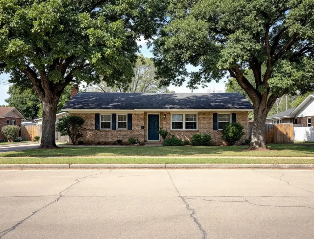 Mid-century ranch home with a low roofline and broad lawn shaded by post oaks on a quiet central Austin street