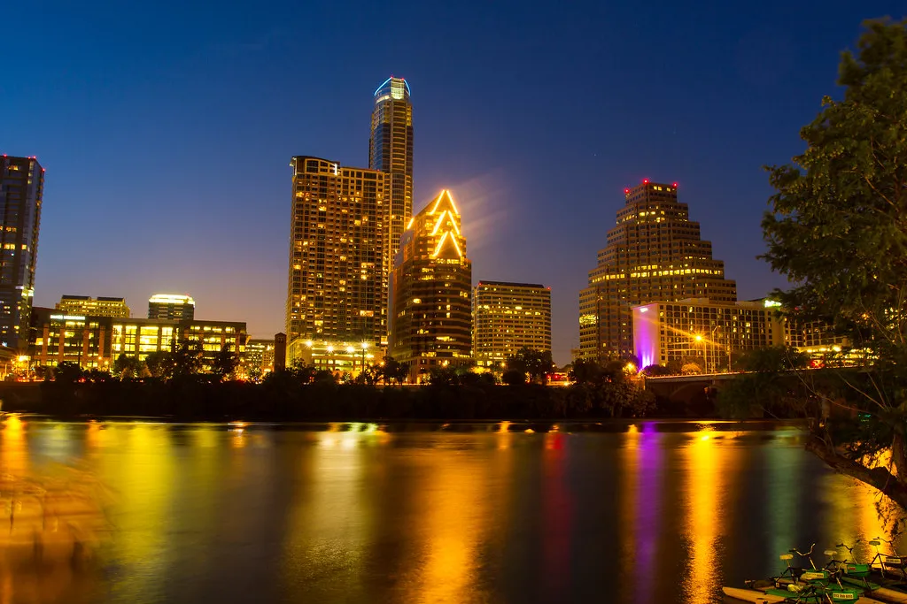 Downtown Austin skyline at dusk reflected in Lady Bird Lake, residential towers glowing